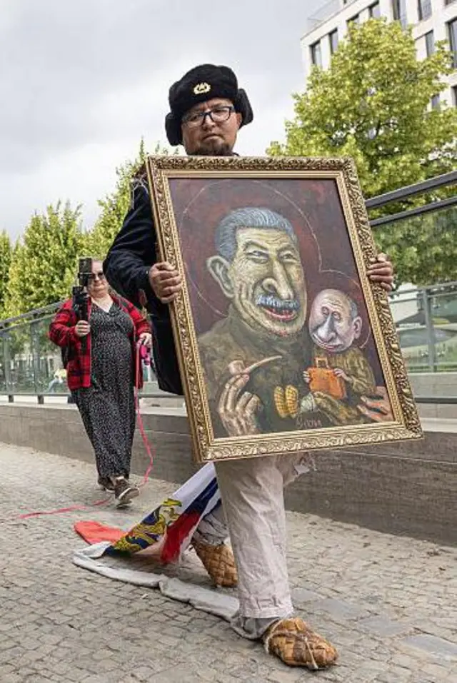 El artista Semyon Skrepetsky camina con uno de sus cuadros