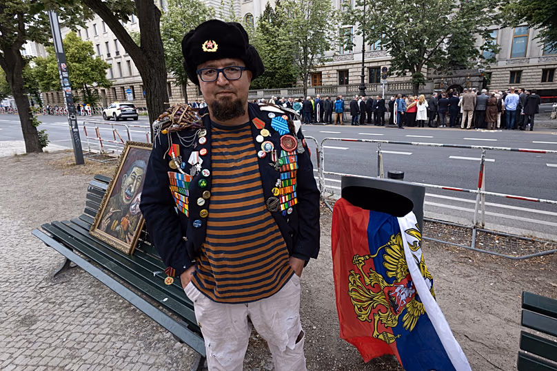 Semyon Skrepetsky poses for a photo with one of his paintings near the Russian Embassy in Berlin, 12 June, 2026