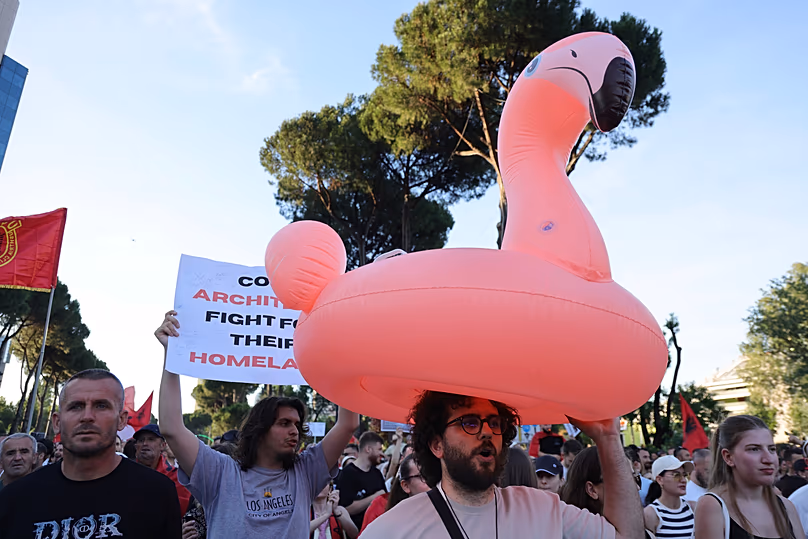 Un manifestante sostiene un flotador de flamenco durante una concentración en Tirana, sábado 13 de junio de 2026.