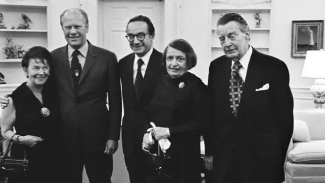 De izquierda a derecha aparecen Rose Goldsmith (madre de Alan Greenspan), el presidente Gerald R. Ford, Alan Greenspan, la escritora Ayn Rand y su esposo Charles Francis «Frank» O'Connor, tras la toma de posesión de Greenspan como presidente del Consejo de Asesores Económicos en el Despacho Oval.