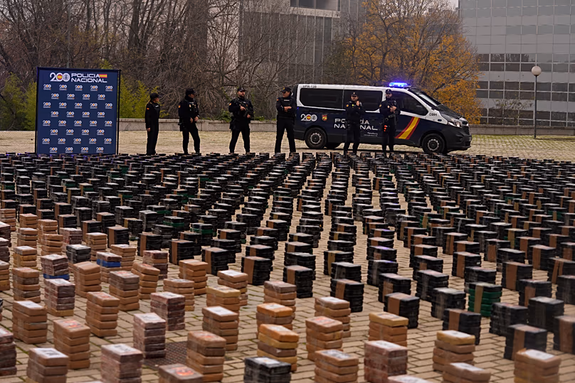 Police officers stand by part of a haul of 11 tons of cocaine, displayed in the patio of a police station in Madrid, Spain, Tuesday, Dec. 12, 2023