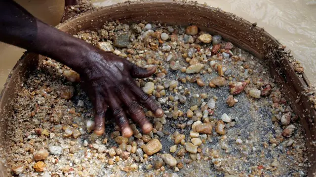 La mano de un minero de diamantes en Sierra Leona tamiza piedras más pequeñas con la esperanza de encontrar las preciosas gemas