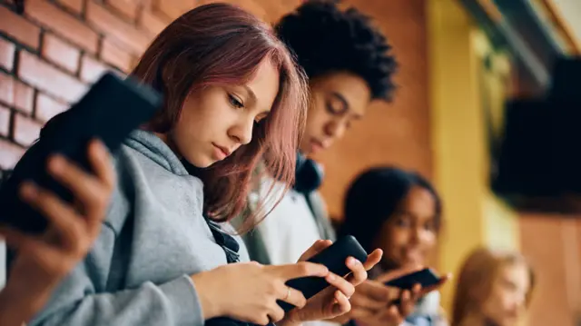 Un grupo de jóvenes con sus teléfonos celulares.
