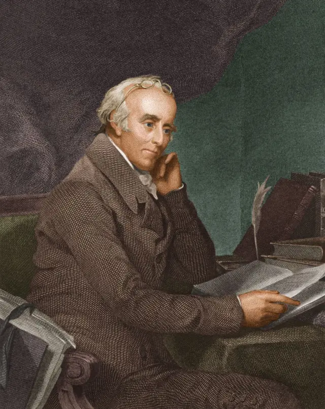 Una ilustración de Benjamin Rush, médico, sentado en su escritorio mirando un cuaderno.