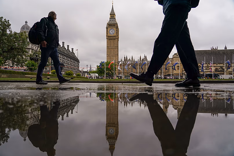 The Elizabeth Tower, commonly known as Big Ben, reflected in a puddle as people walk past in London, 3 June, 2026