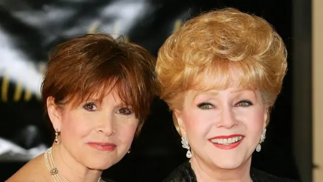 Carrie Fisher y Debbie Reynolds miran sonrientes a la cámara.
