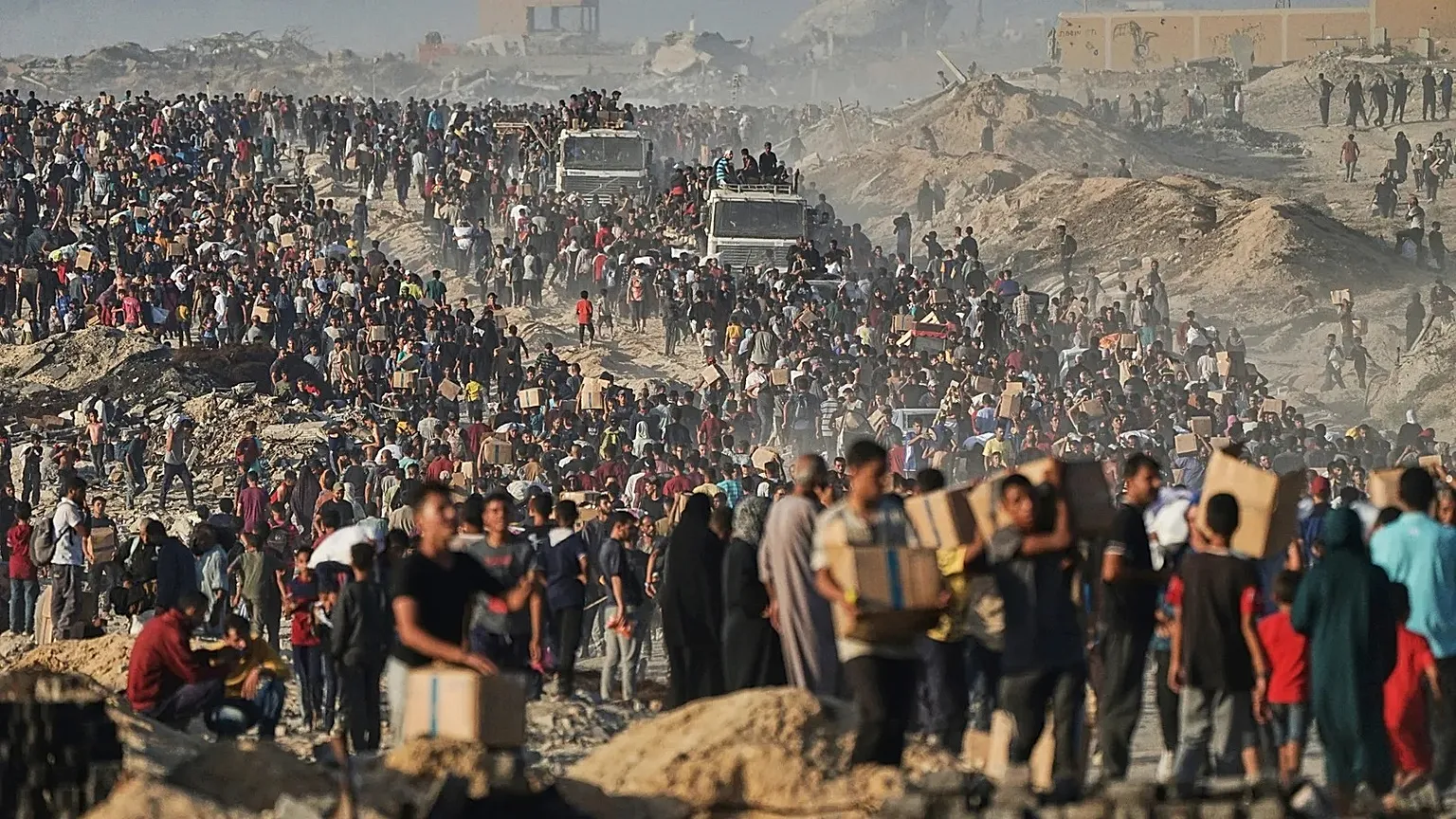 Palestinians carry sacks and boxes of food and humanitarian aid that was unloaded from a World Food Programme convoy near Gaza City, 16 June, 2025