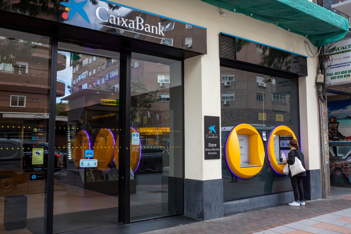 Una señora saca dinero del cajero en una oficina de CaixaBank (La Caixa)