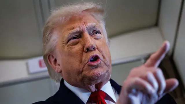 Primer plano de Trump de pie, señalando con el dedo mientras habla con los periodistas a bordo del Air Force One