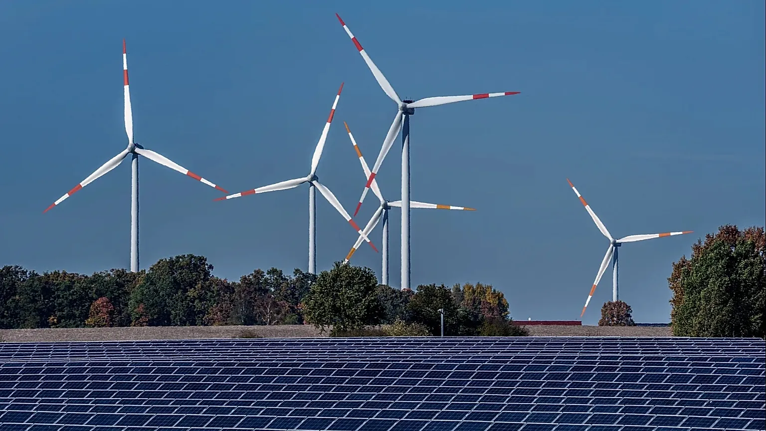 Wind turbines turn behind a solar farm in Rapshagen, Germany, Thursday, Oct. 28, 2021. 