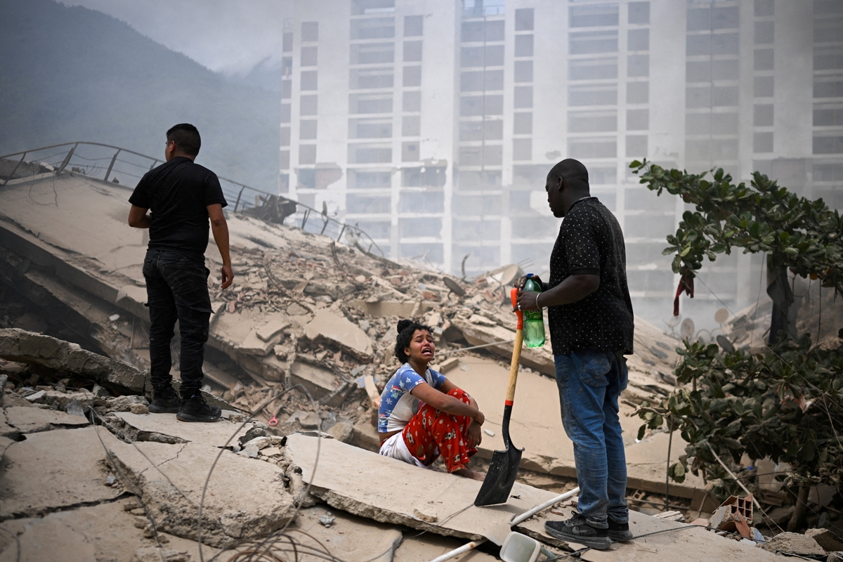 Una mujer observa cómo se busca a posibles víctimas entre los escombros de los edificios derrumbados, tras los terremotos ocurridos en La Guaira, en Venezuela. 25 de junio de 2026. REUTERS/Gaby Oraa