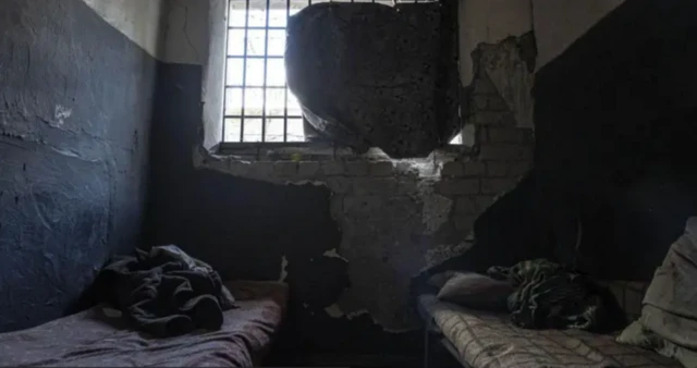 Una fotografía de un edificio que las fuerzas rusas supuestamente usaron como prisión en Izium antes de retirarse de la región ucraniana de Járkov, en septiembre de 2022, muestra una celda pequeña y oscura, con pintura desprendida de las paredes, dos camas con colchones sucios y un pequeño trozo de tela que cubre parcialmente la ventana.
