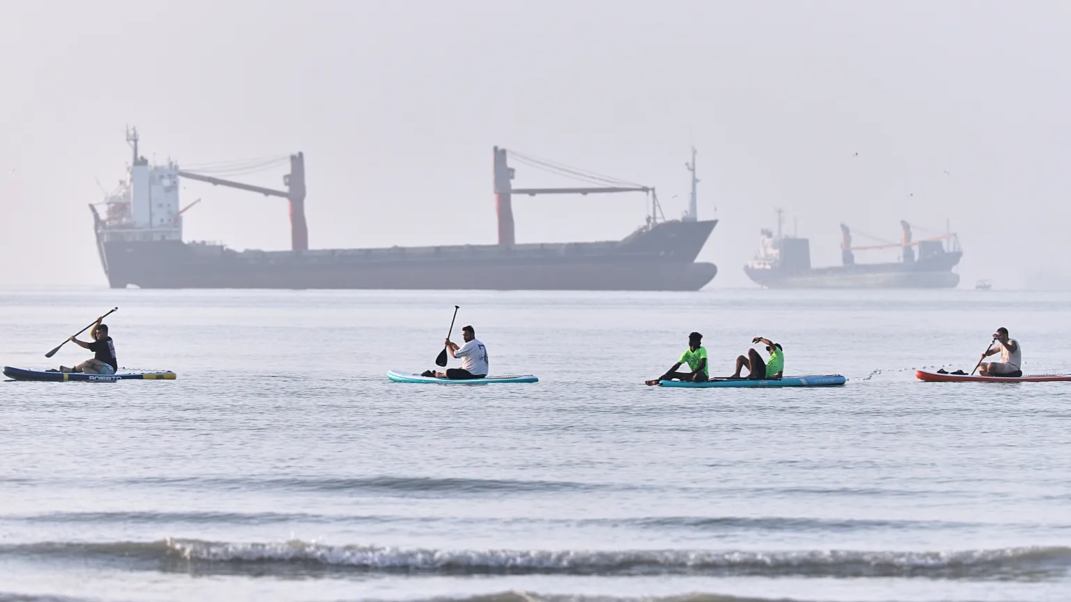 People paddle along the shoreline as cargo ships are anchored in the Strait of Hormuz off Bandar Abbas, Iran, Monday, June 1, 2026. (Amirhosein Khorgooi/ISNA via AP)