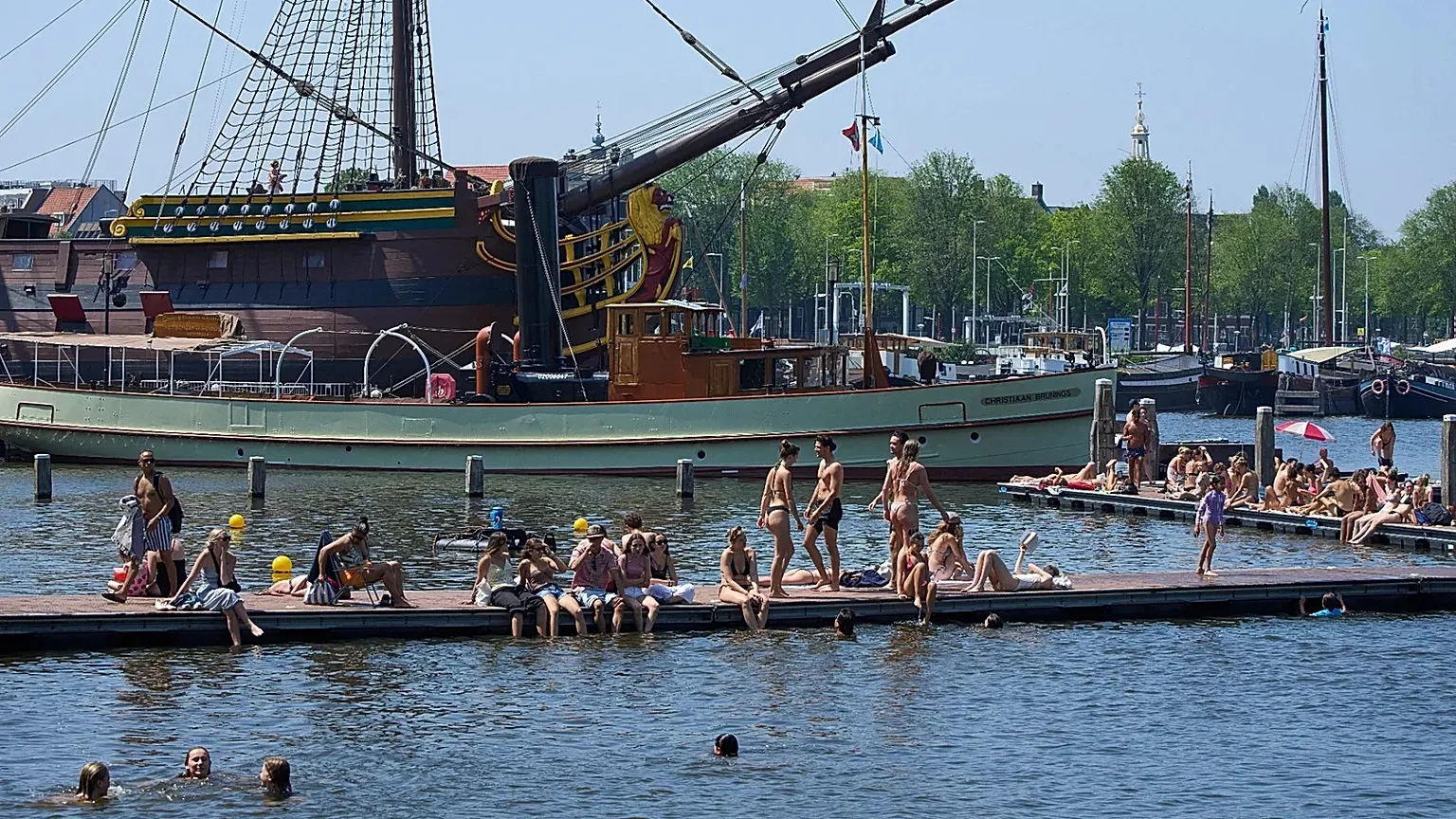 People cool off near the replica of a 18th-century VOC (Dutch East India Company) vessel during a heatwave in Amsterdam, Netherlands, Thursday, June 25, 2026.