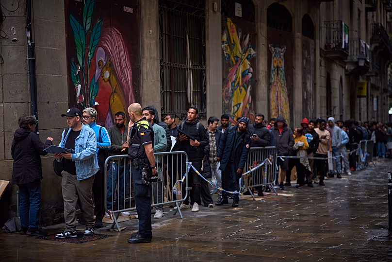 Migrants queue outside Barcelona City Hall to obtain paperwork needed to apply for Spain's immigration amnesty, 29 April, 2026