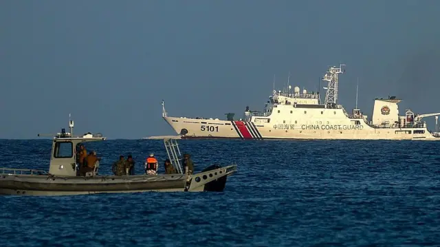Una lancha rápida de la Infantería de Marina filipina patrulla frente a la costa de la isla Thitu, bajo dominio filipino, mientras un buque de la Guardia Costera china se aproxima, en el disputado Mar de China Meridional, el 3 de mayo de 2026. La isla Thitu, bajo dominio filipino, también conocida como Pagasa, forma parte del archipiélago de las Spratly en el Mar de China Meridional.