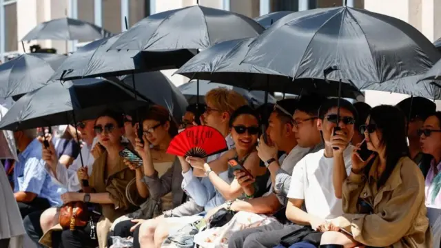 Personas protegiéndose del sol con sombrillas durante la Semana de la Moda de Milán