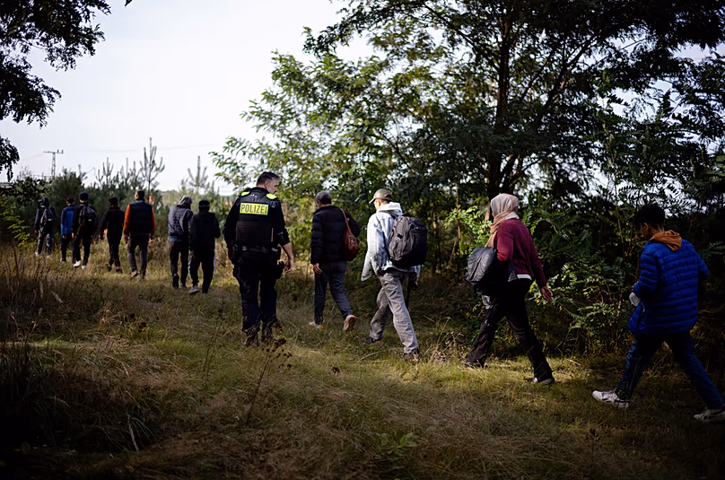 FILE - Police officer escorts a group of migrants who illegally crossed the border from Poland into Germany, southeast of Berlin, Germany, on Oct. 11, 2023