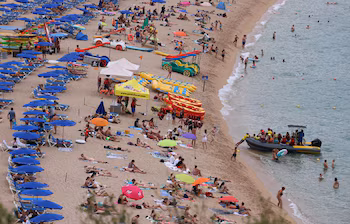 Turistas disfrutan de la playa en el mar Mediterráneo en Lloret de Mar. (REUTERS/Nacho Doce)