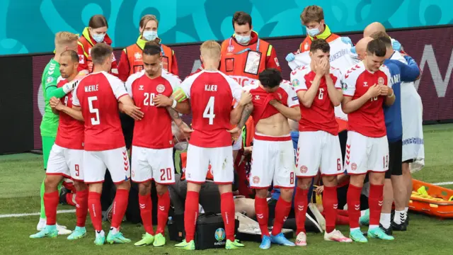 Los jugadores de Dinamarca forman un círculo para proteger a su compañero Christian Eriksen mientras recibe asistencia médica durante el partido del Grupo B de la Eurocopa 2020 entre Dinamarca y Finlandia en 2021.