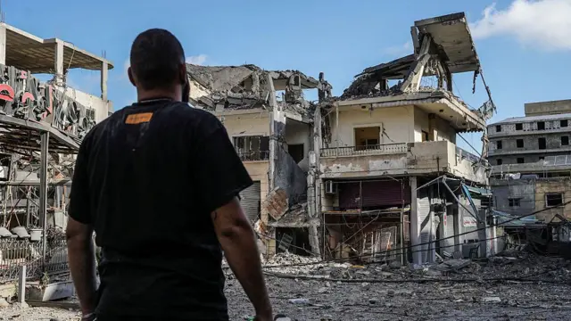 Un hombre está de pie frente a un edificio gravemente dañado en el centro de Nabatieh el 15 de junio de 2026.
