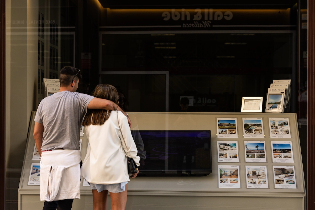 Dos jóvenes miran los anuncios de viviendas en venta en una inmobiliaria. (Tomàs Moyà/Europa Press)