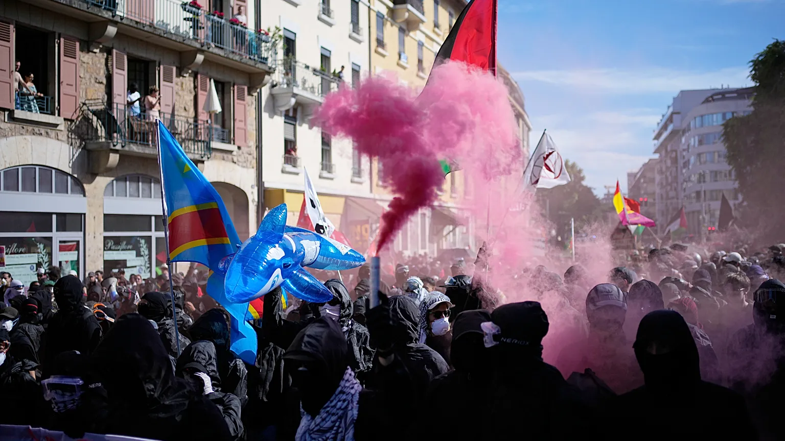 Protesters set off a pink flare during a "No G7" demonstration in Geneva, Switzerland, Sunday, June 14, 2026, ahead of the G7 summit scheduled to take place June 15-17. (AP Ph