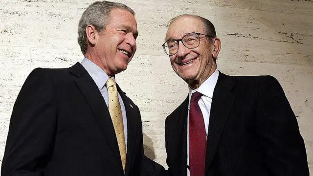 George W. Bush y Alan Greenspan son fotografiados juntos. Sonríen y posan para las cámaras.