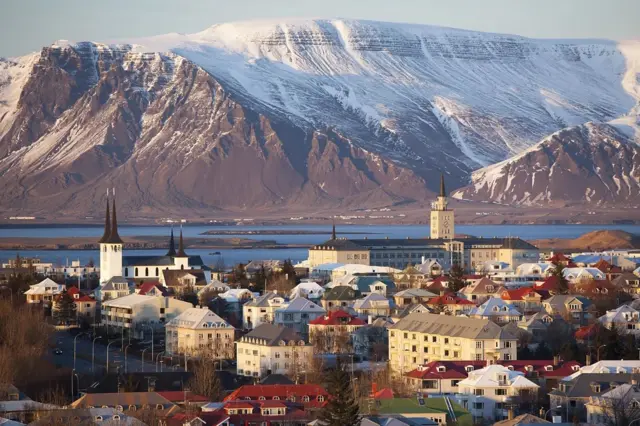 Una panorámica de una ciudad de Islandia, con un increíble atardecer y una montaña congelada en el fondo.