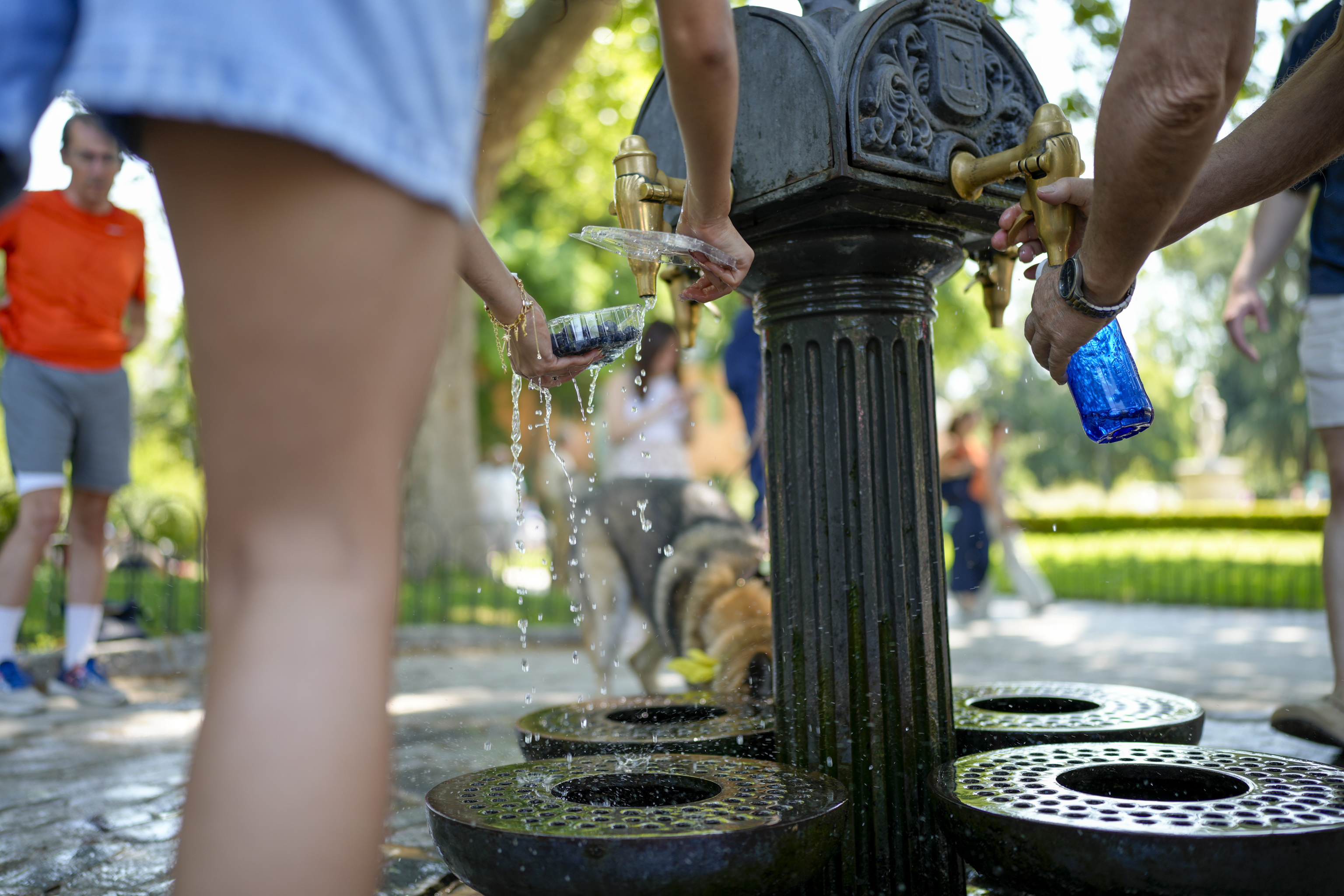 Dos personas se refrescan en una fuente de Madrid.