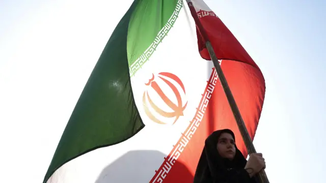 Una mujer sostiene una bandera iraní en una calle de Teherán, Irán.