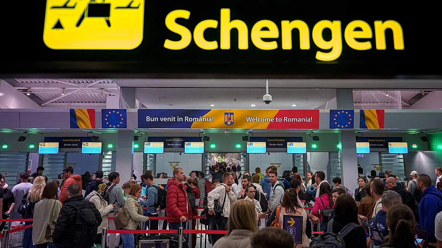 Passengers arriving at the Henri Coanda International Airport pass under a Schengen Information sign, in Otopeni, near Bucharest, Romania.