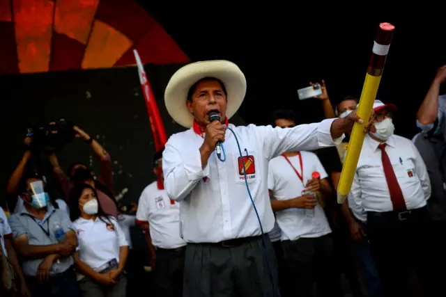 Pedro Castillo habla al micrófono mientras sujeta un gran lápiz en un mitin en 2021. 