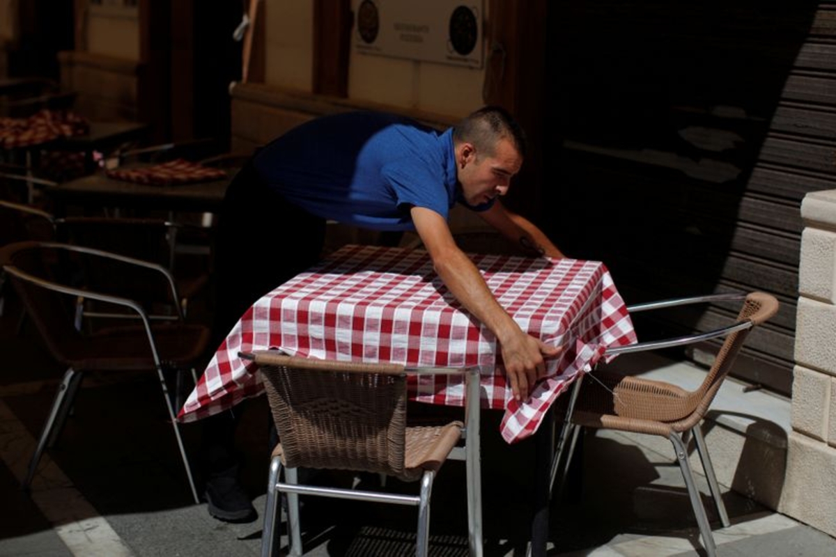 Un camarero arregla un mantel en la terraza de un restaurante en el centro de Ronda, España, 28 de julio de 2016. REUTERS/Jon Nazca - S1BETSECFGAA