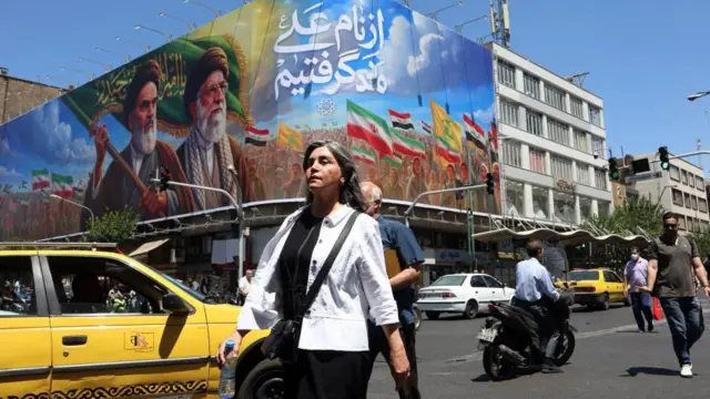 Unos iraníes pasan junto a una valla publicitaria con las imágenes de los fallecidos líderes supremos de Irán, el 15 de junio.