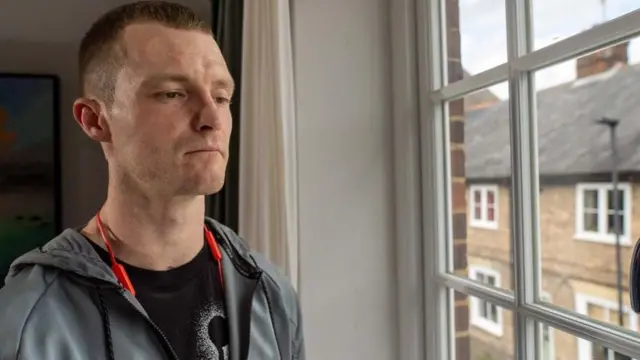 Jamie con rostro serio, mirando por la ventana 