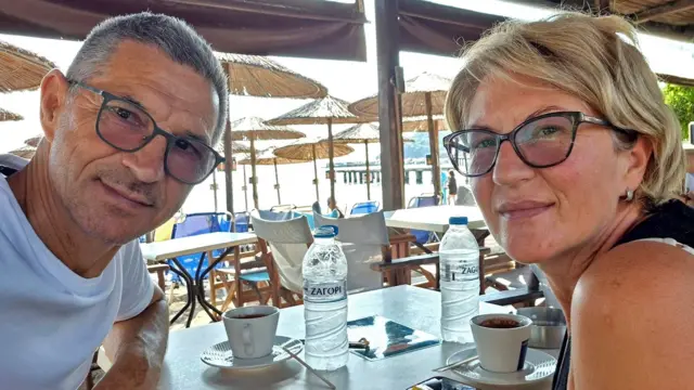 Karovic Ljubisa y su esposa Svetlana Grković, sonriendo para una foto en un bar que parece estar en un complejo turístico.