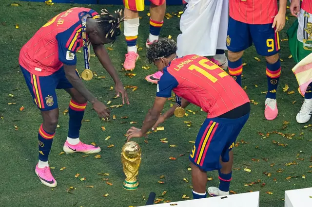 Nico Williams y Lamine Yamal ponen la Copa del Mundo en el césped y celebran a su alrededor.