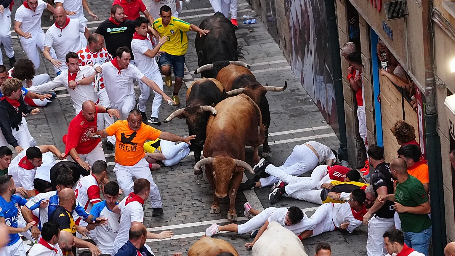 Revellers run alongside La Palmosilla's fighting bull during the sixth running of the bulls at the San Fermín festival, 12 July, 2026