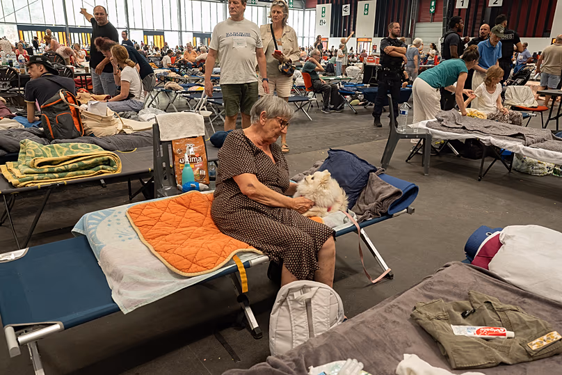 A woman caresses her dog at a shelter set up in the Bordeaux Exhibition Centre for those evacuated amid the raging wildfires, Bordeaux, France, Sunday, July 26, 2026