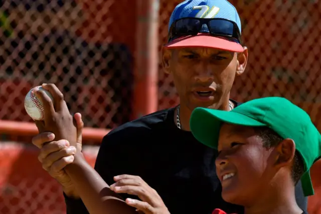 Un entrenador le enseña a un niño como lanzar la pelota.