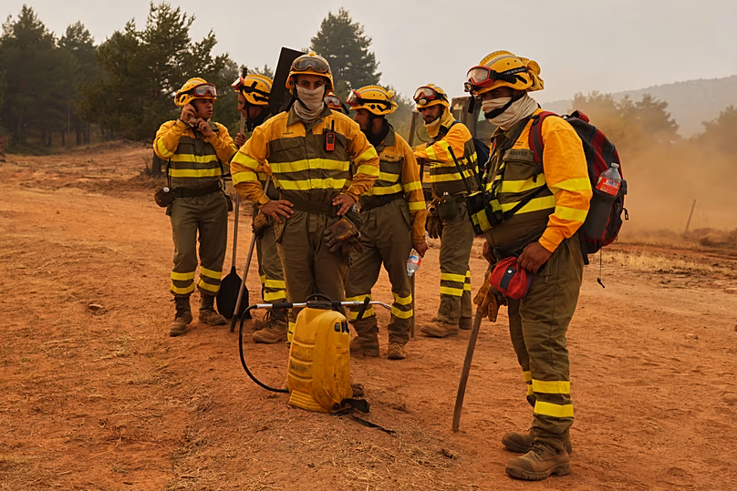 Forest rangers take a break before returning to work on the fire near Condemios de Arriba, Guadalajara province, Spain, Wednesday, July 22, 2026.