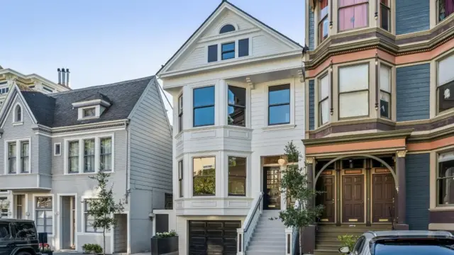 Tres casas en una calle residencial de San Francisco. Las viviendas de tres plantas lucen limpias y bien mantenidas, con plantas y árboles bien cuidados en el exterior.
