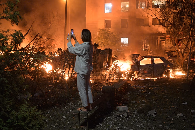 A woman takes photo of destructions following Russian missile attacks in Kyiv, Ukraine, Monday, July 6, 2026. 