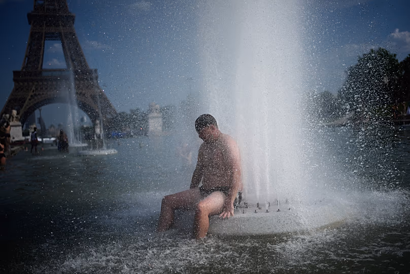 Una persona se refresca en la fuente de Trocadero cerca de la Torre Eiffel durante una ola de calor en París, 24 junio, 2026
