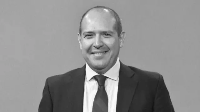 Una foto de torso en blanco y negro de Alejandro Leyva, vestido con saco y corbata