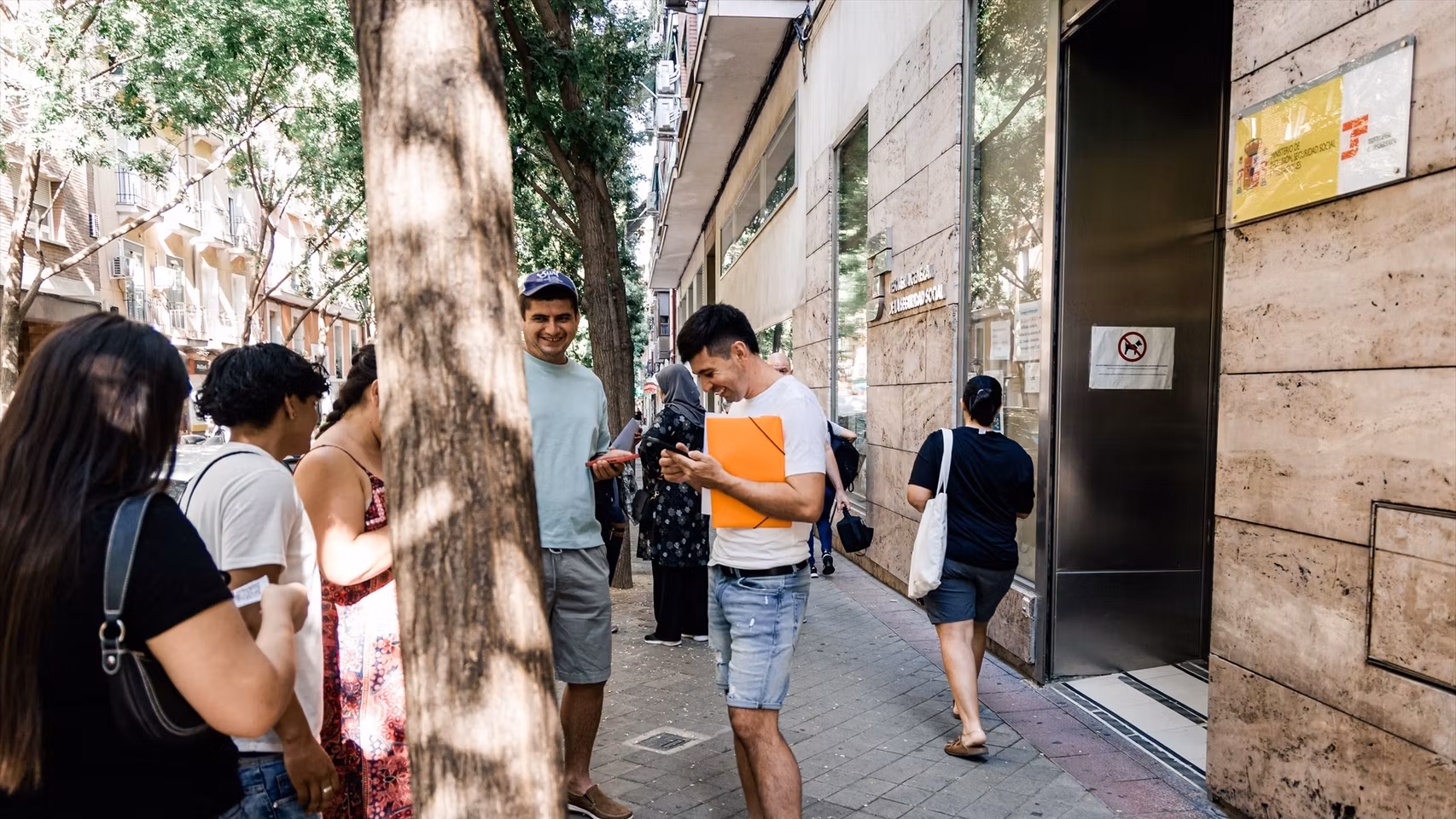 Varias personas migrantes esperan en el exterior de una oficina de la Seguridad Social el pasado 30 de junio.