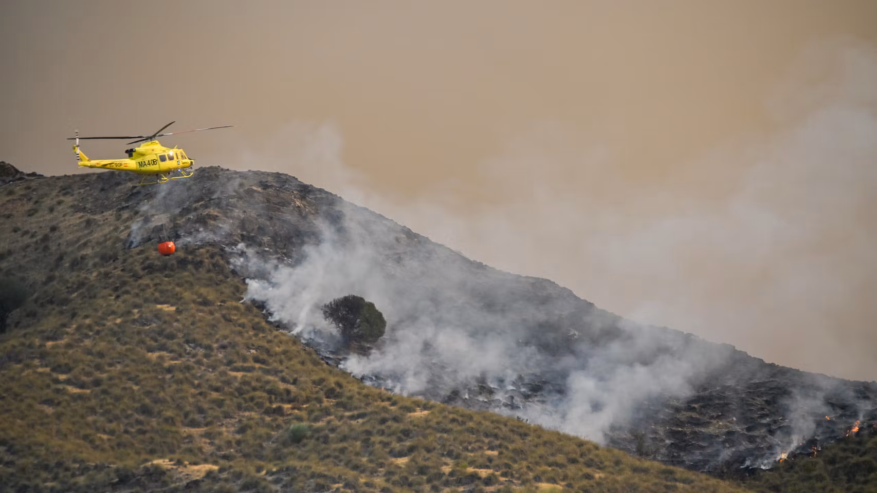Un helicóptero trata de apagar las llamas.