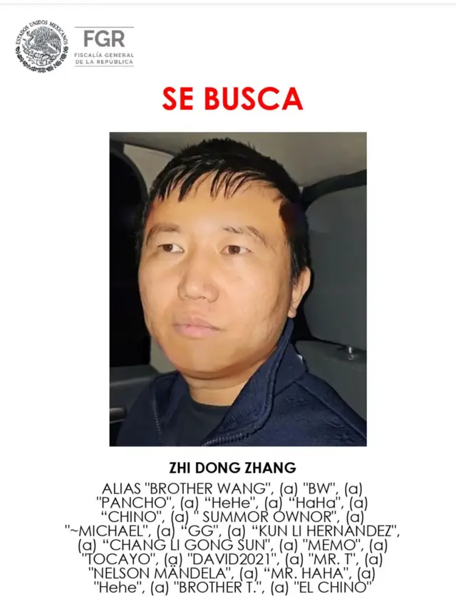 Un cartel muestra el rostro de Zhang, quien tiene el pelo corto y oscuro. Encima de él se lee "se busca". Debajo aparece una lista de alias, entre ellos Pancho, China y Hermano T.