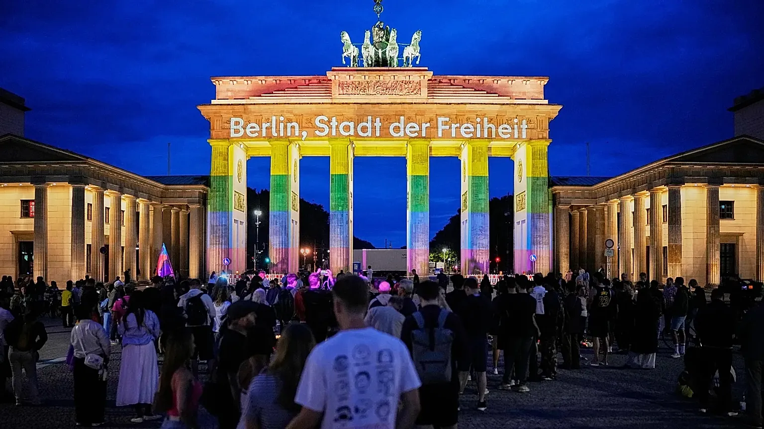 People gather in front of the Brandenburg Gate illuminated with the message "Berlin, city of freedom", commemorating the victims, after a car rammed into a crowd at the Pride 